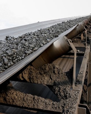 Coal moving on conveyor with worker walking to inspection area