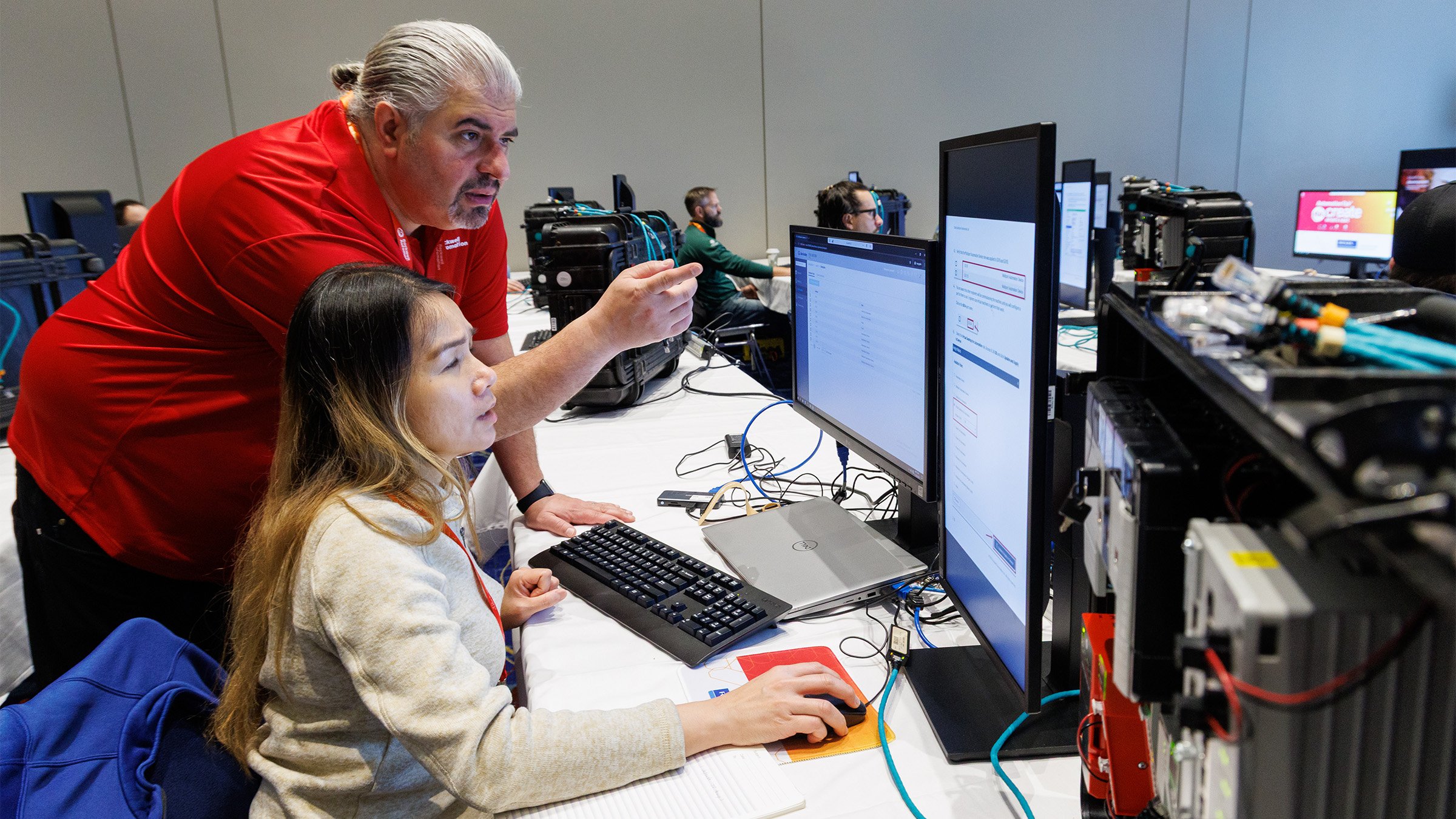 A man pointing to a computer screen with a student at a Hands-on Lab