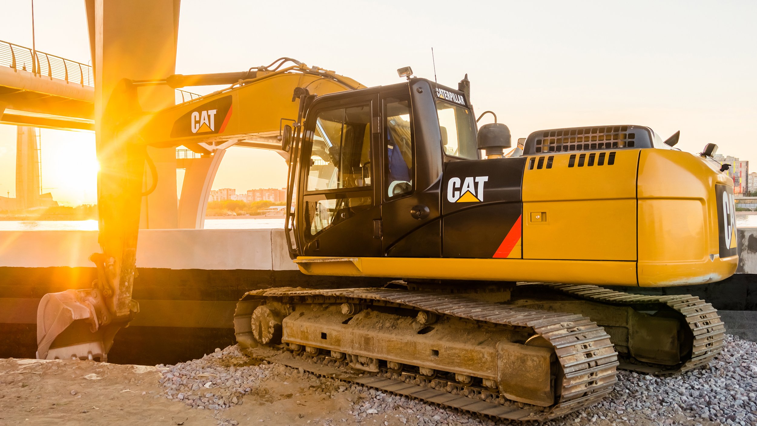 Construction of street of new emankment at St. Petersburg, Russia. Excavator CAT Caterpillar. Tractor with sunset shines. earthmoving, transportation. construction machinery
