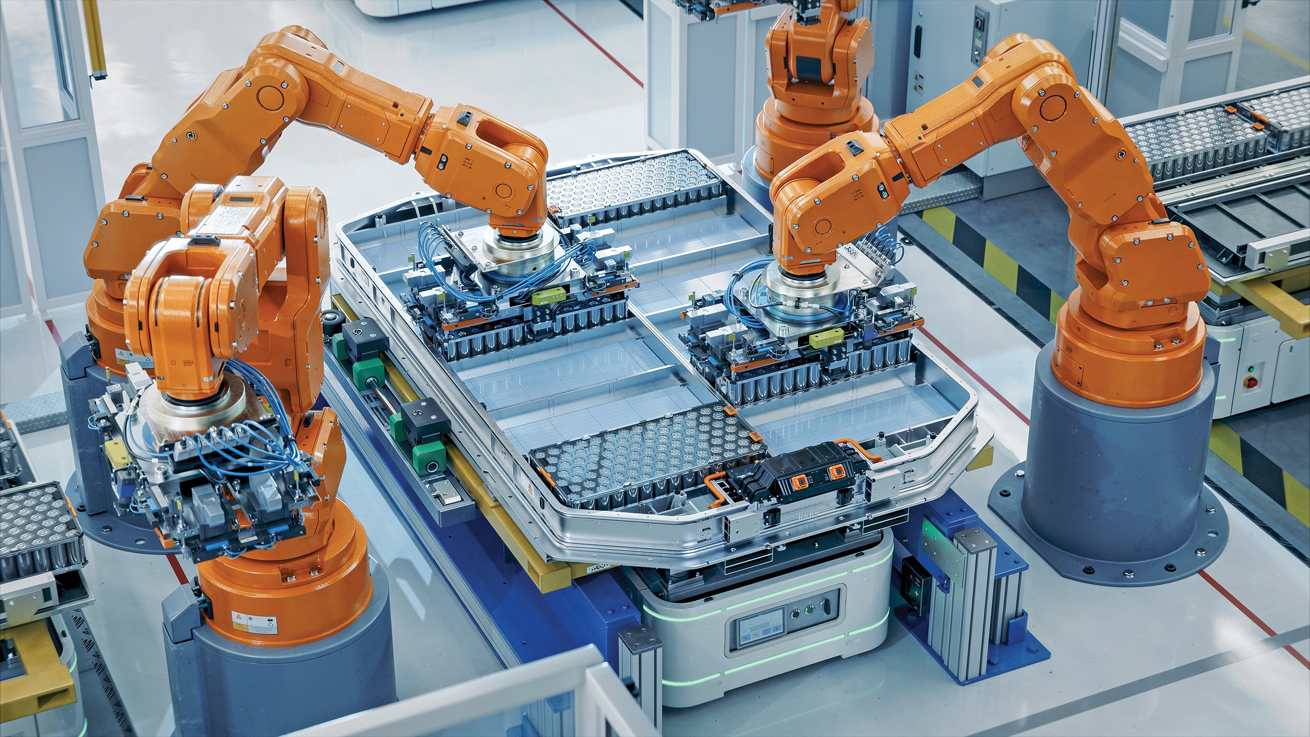 Orange Industrial Robot Arms Assemble Skateboard style EV Battery Pack on Automated Production Line. Electric Car Smart Factory Equipped with Robotic Arms. Battery Module Installation Process Top View