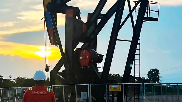 bcp group and magenta employee stands in front of well pump using artificial lift technology at oil and gas site