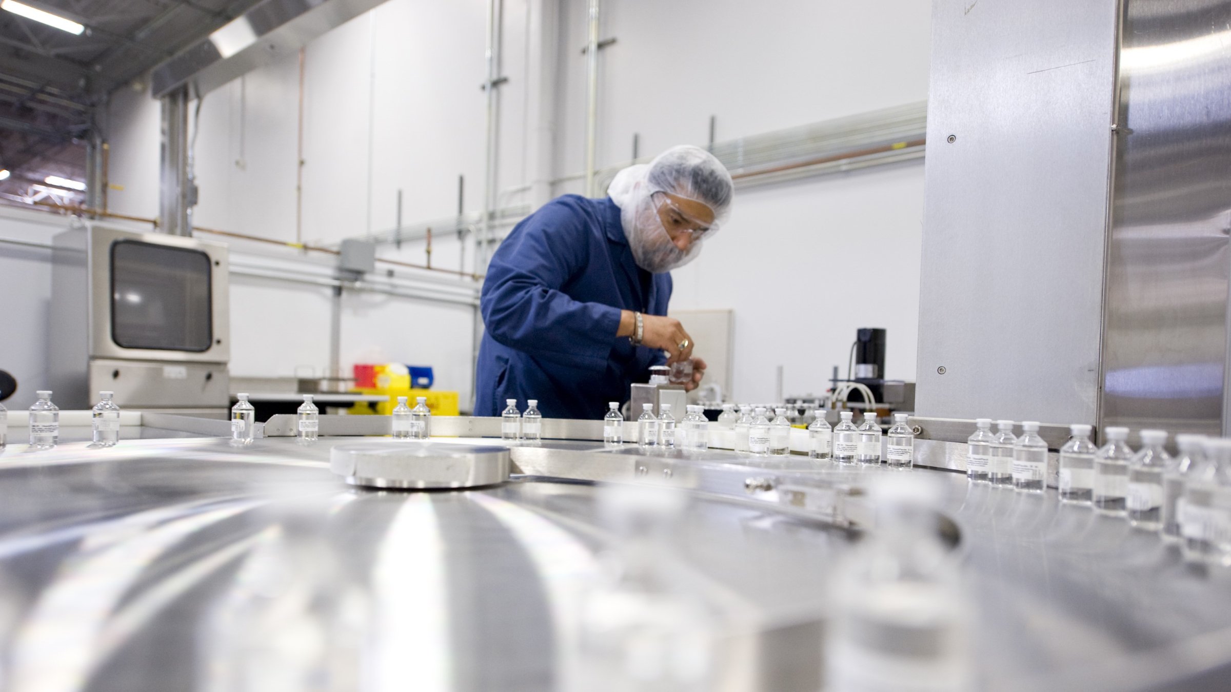 Un hombre concentrado en operar una máquina en un taller, usando equipo de seguridad y rodeado de herramientas