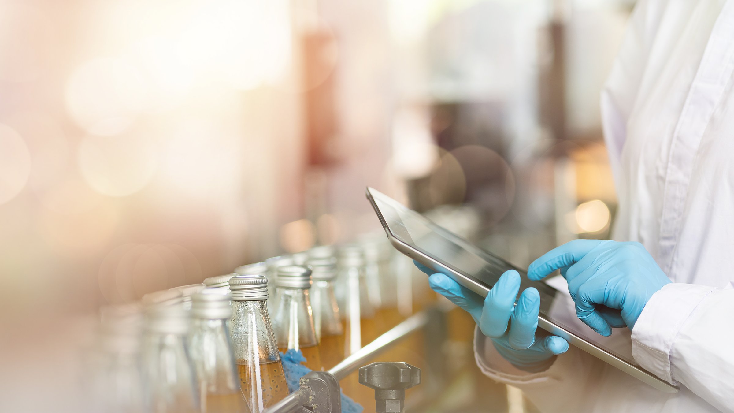 Hands of worker working with digital tablet check product on the conveyor belt in the beverage factory. Worker checking bottling line for processing. Inspection quality control.