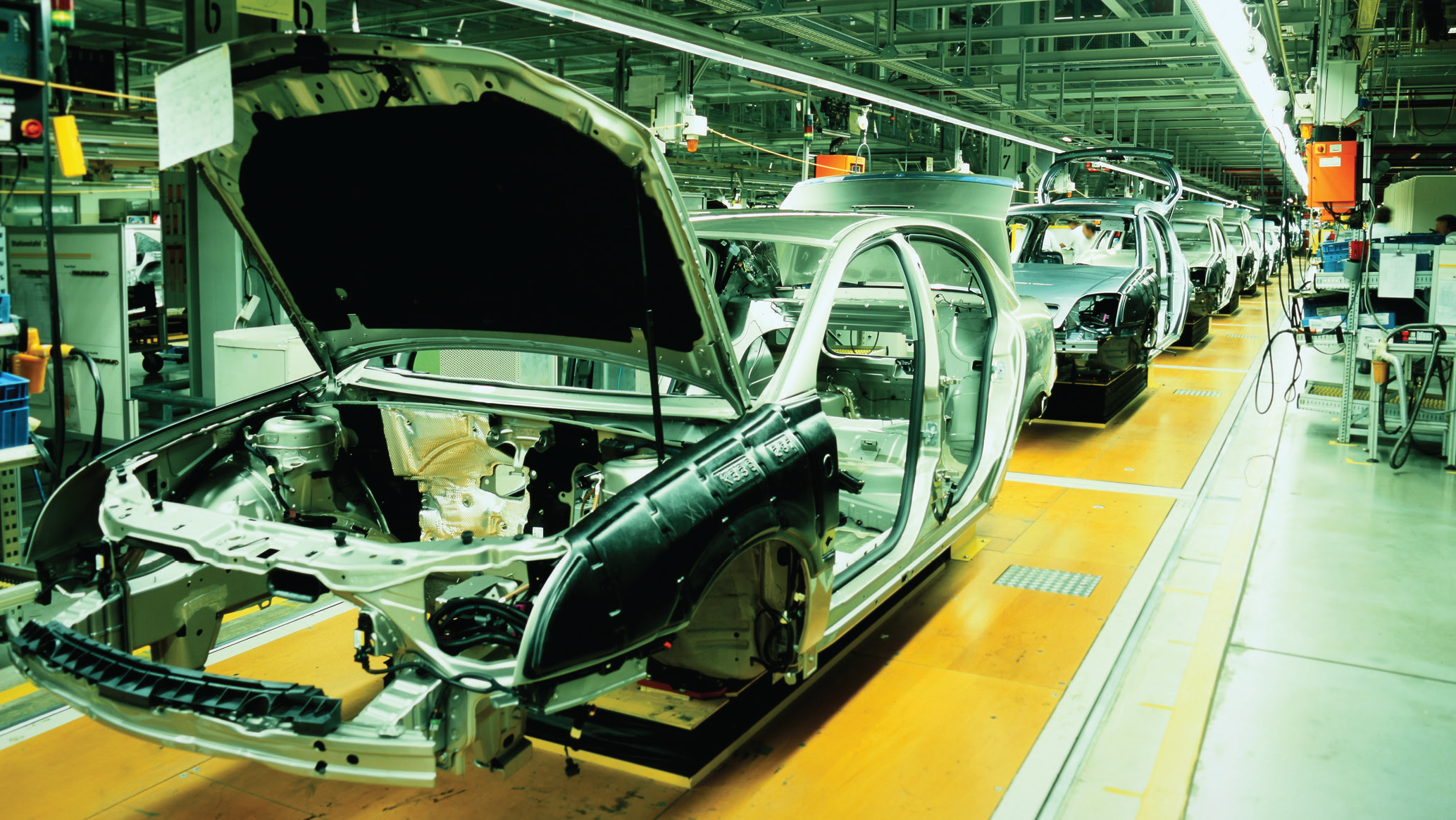 Car production line with unfinished cars in a row cars bodies in a big hall on long production line