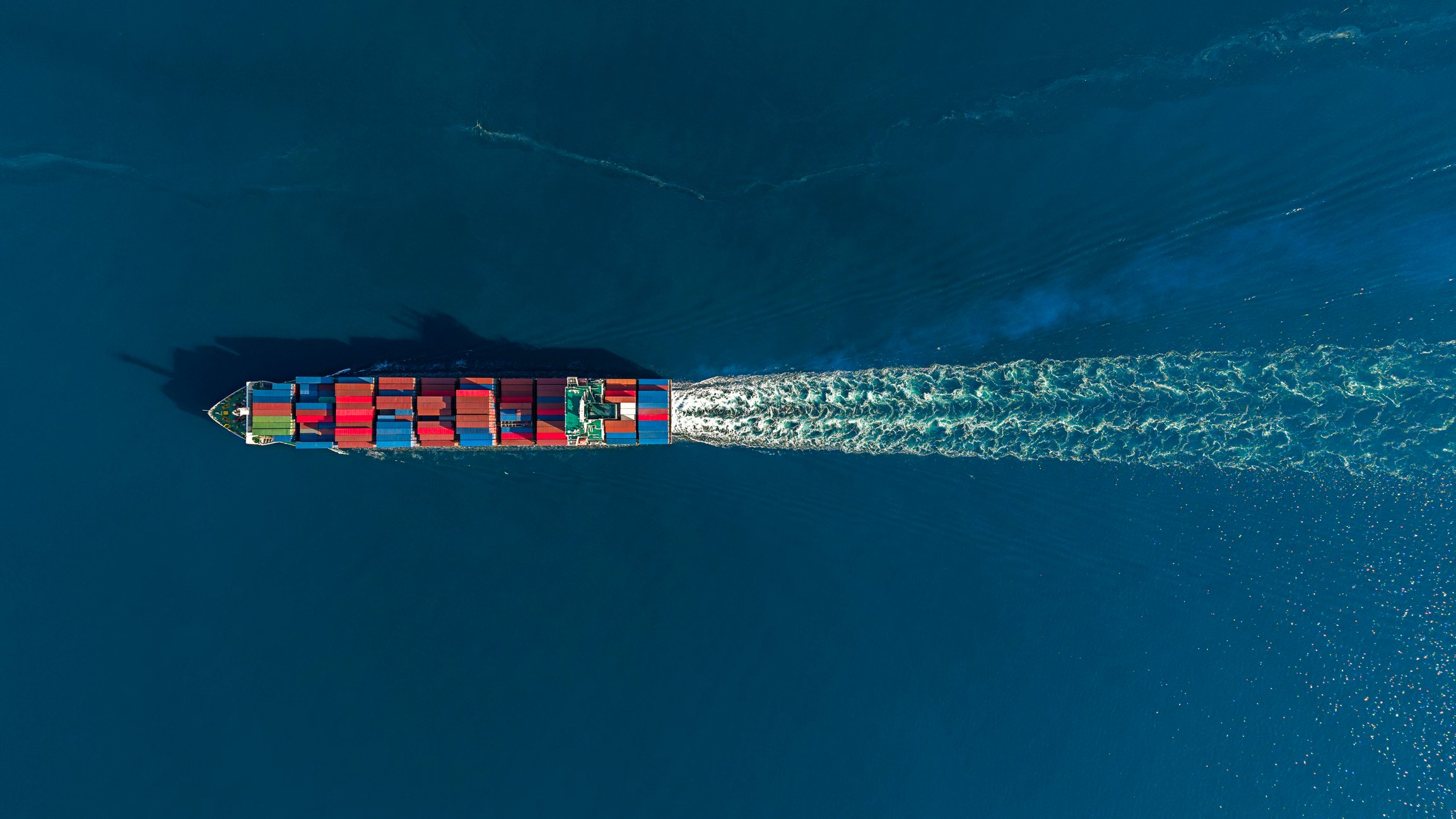 Cargo ship carrying shipping containers moving through the ocean