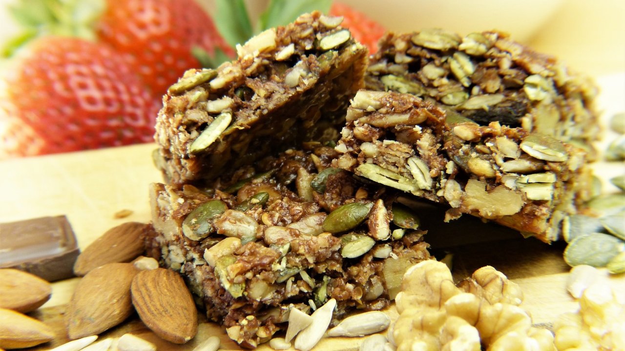 Cereal bars with nuts and almonds and strawberries in the background