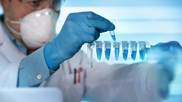 researcher in lab uses pipette to fill vials