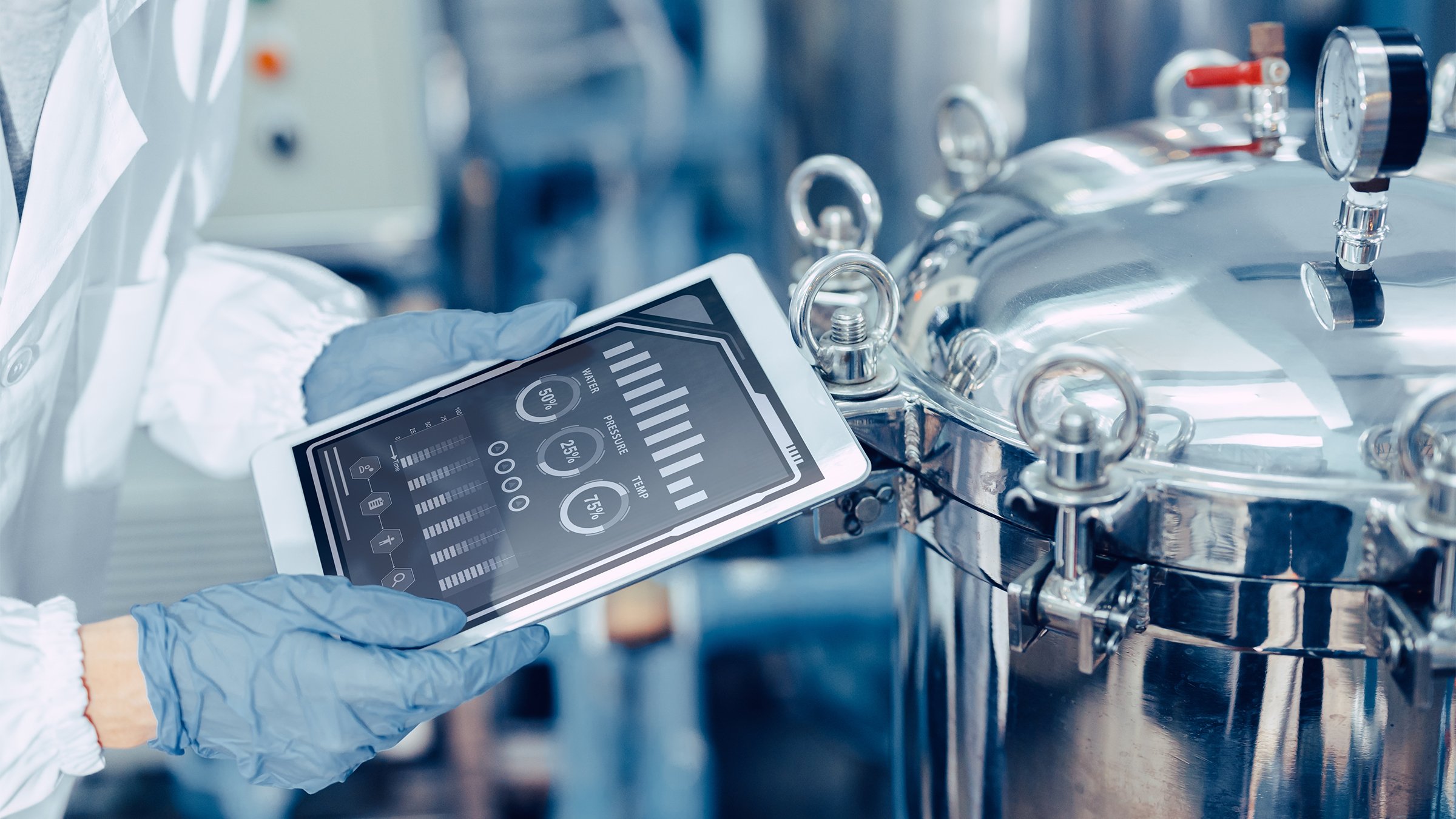Close-up of an engineer using a tablet to monitor a high-pressure tank in a food and beverage plant.