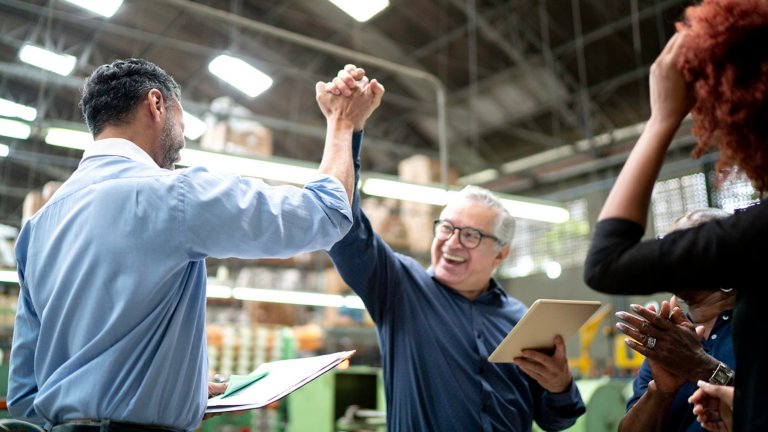 Compañeros de trabajo celebran buenas noticias en una planta