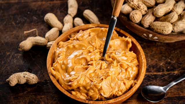 peanut butter and inshell peanuts on a cutting board