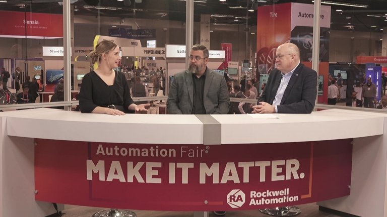 Three people from Rockwell Automation sitting at a ROK Studios desk at Automation Fair talking.