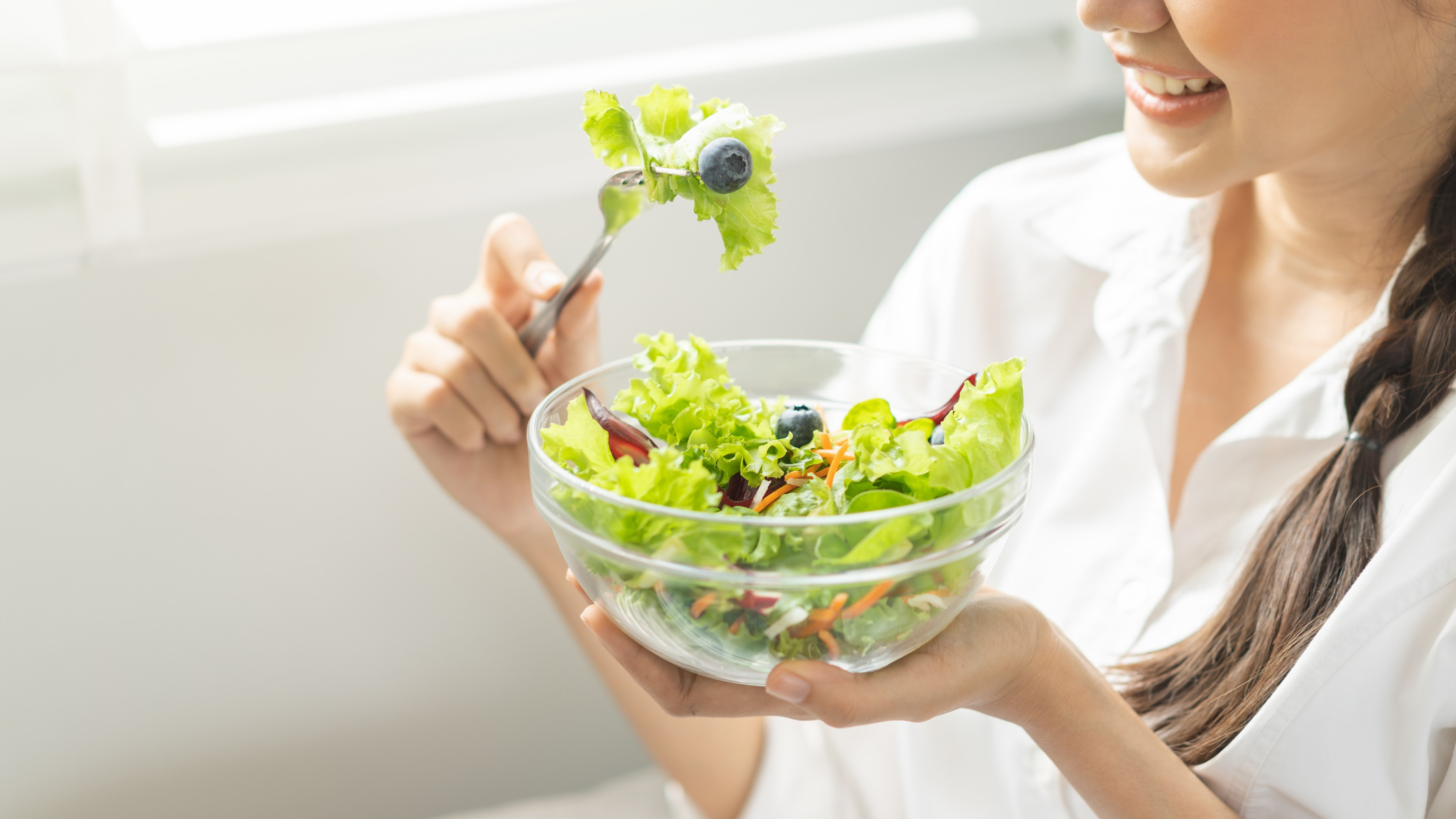 Diet, Dieting asian young woman, girl hand use fork at lettuce on mix vegetables, green salad bowl, eat food low fat to good body sitting on sofa at home. Nutritionist female, Weight loss for healthy