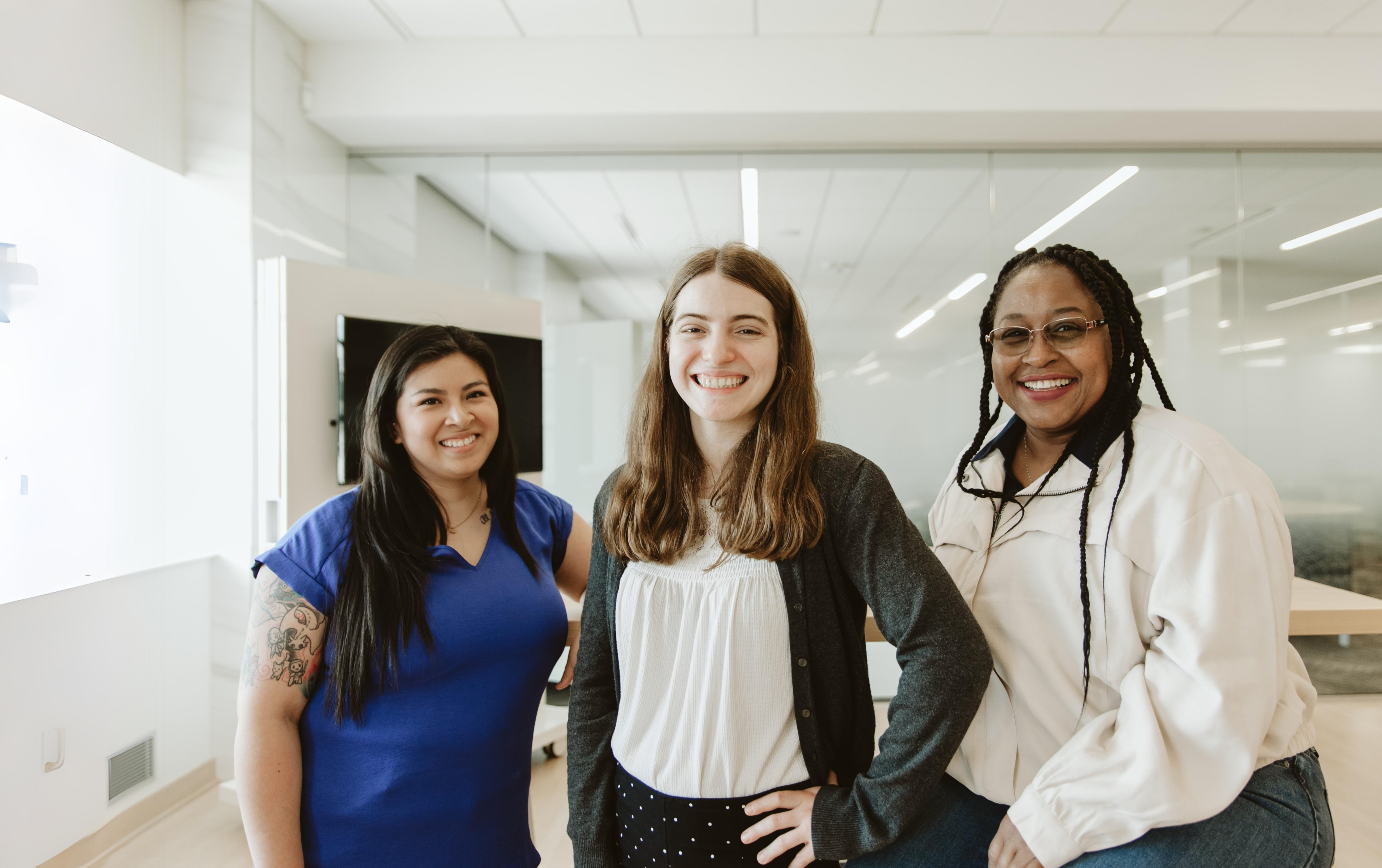 Three women smiling together in an office