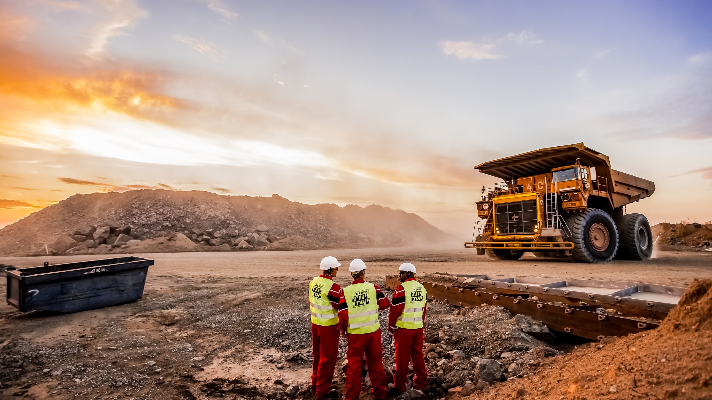 Large Dump Trucks transporting Platinum ore for processing with mining safety inspectors in the foreground