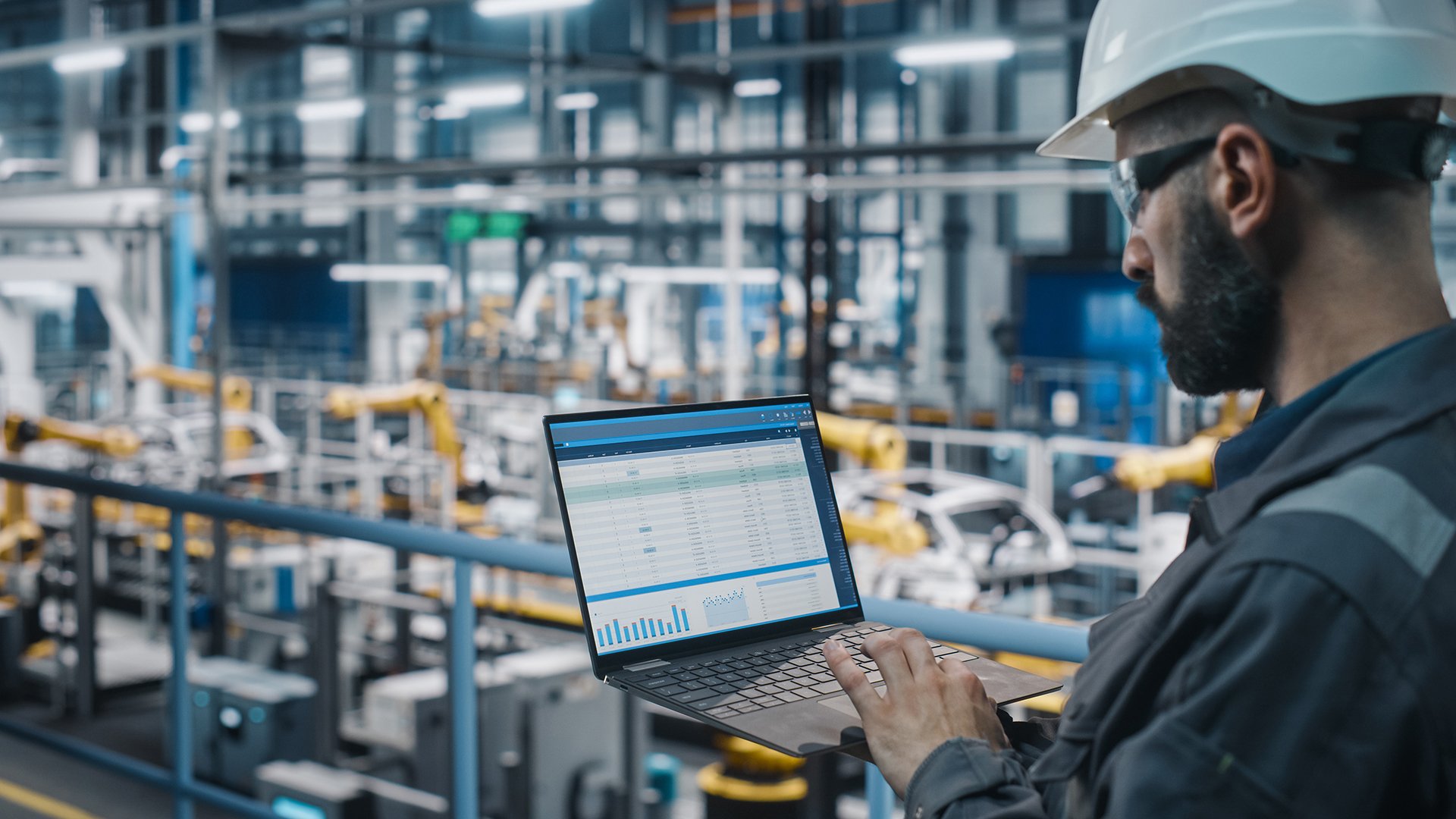 Engineer on a industrial plant floor holding a laptop requiring patch management solutions