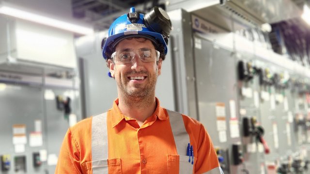 operations manager stands in front of mccs in electrical room at mine site