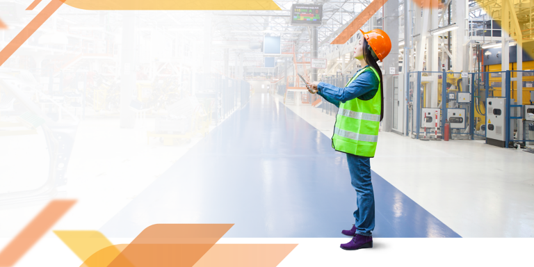 Woman with orange helmet holding tablet and checking the machine.