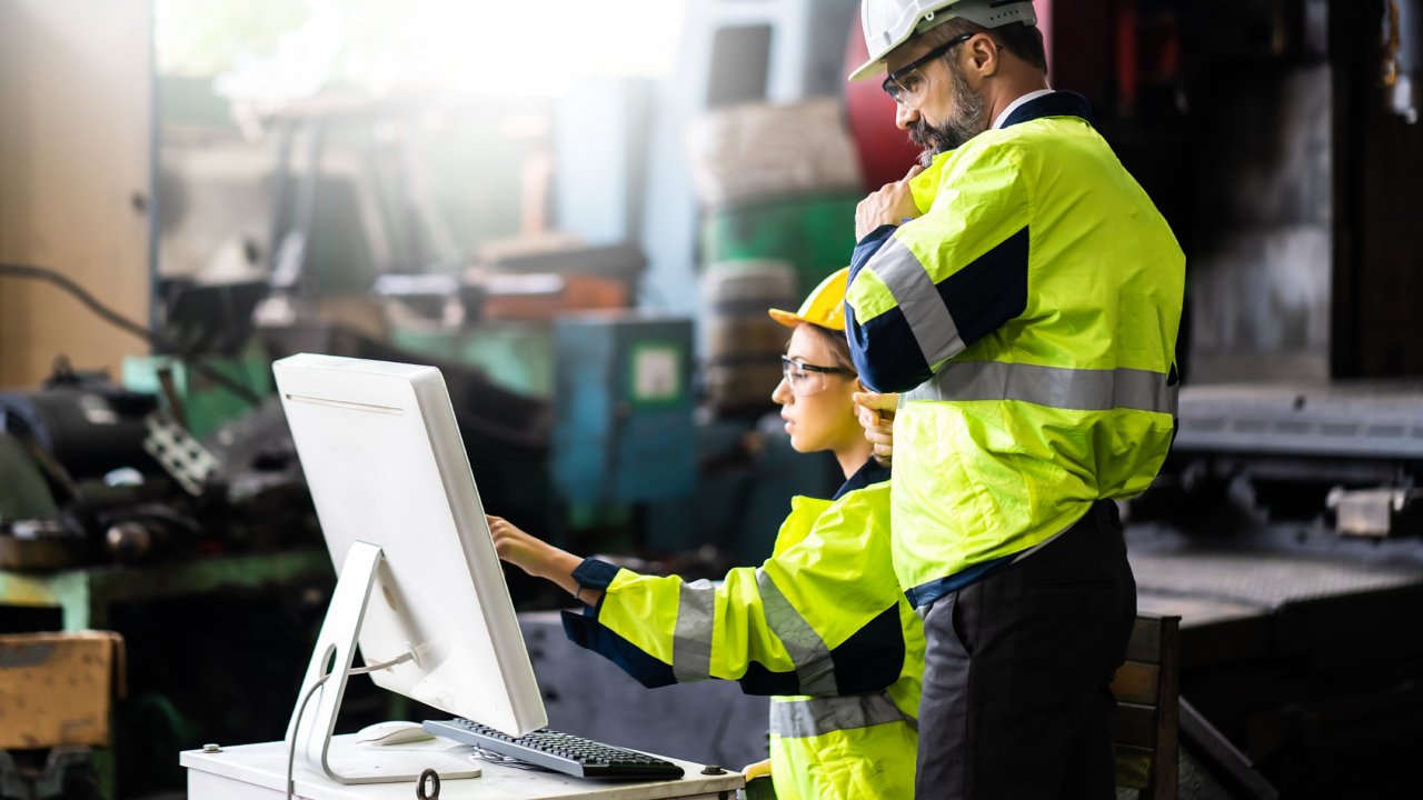 Engineer man and woman worker working on Personal.computer in Heavy Industry Manufacturing Facility. 