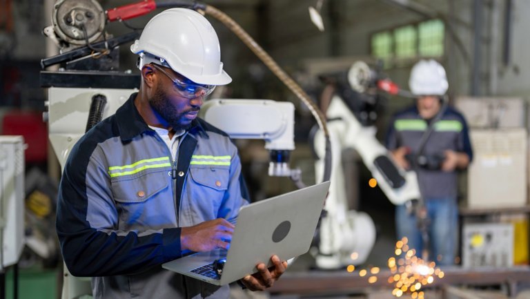African mechanical engineer working for maintenance or repairing robotic welding machine in factory. Maintenance and repairing work in modern industry concept.