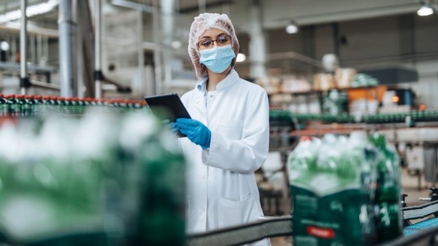 瓶詰め工場で品質管理検査を実施している女性エンジニア