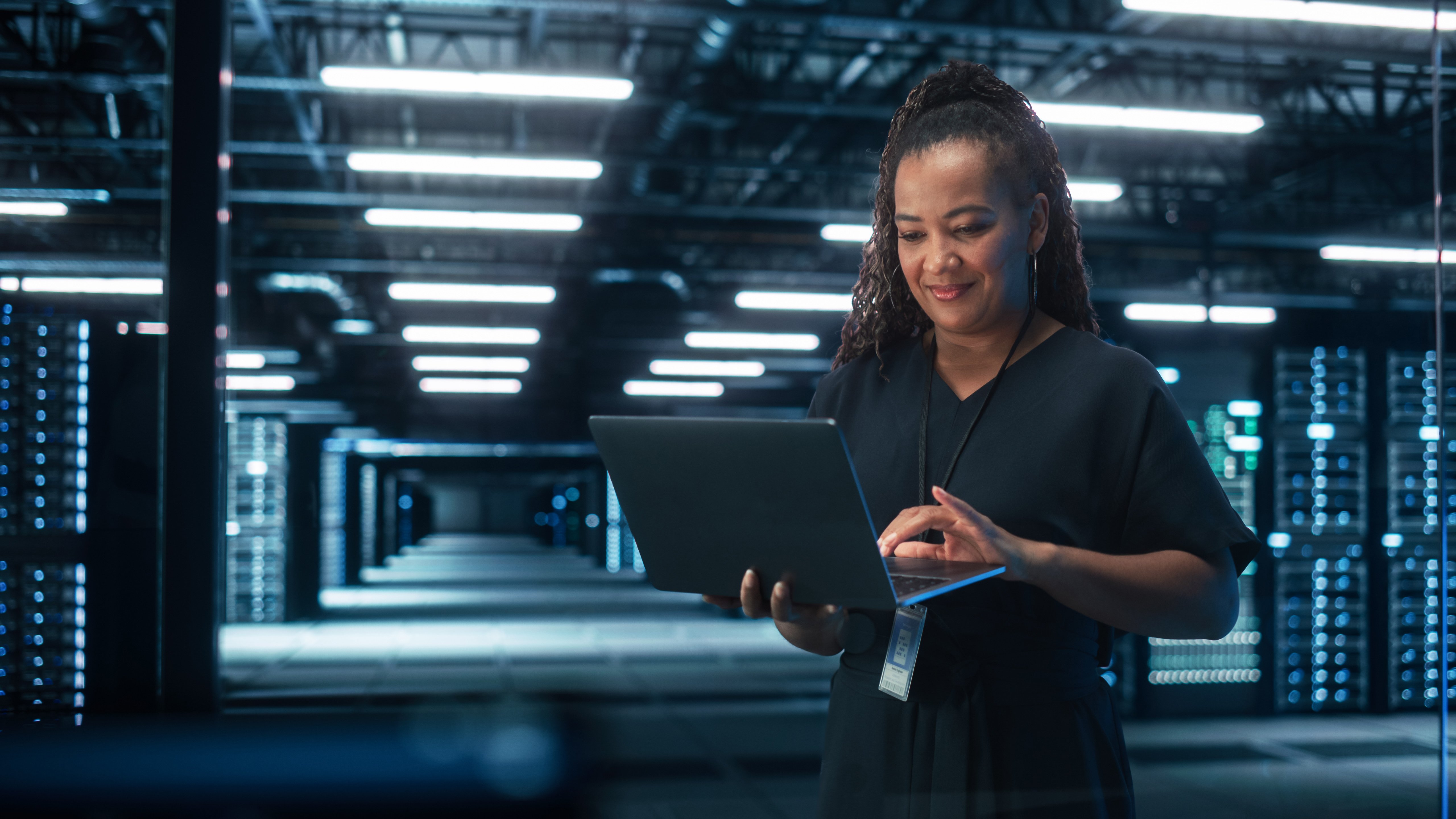 Chief Technology Office Using Laptop Computer, Standing in Big Office Data Center. System Administrator working with SAAS, Cloud Web Services. Cybersecurity Digital Transformation concept