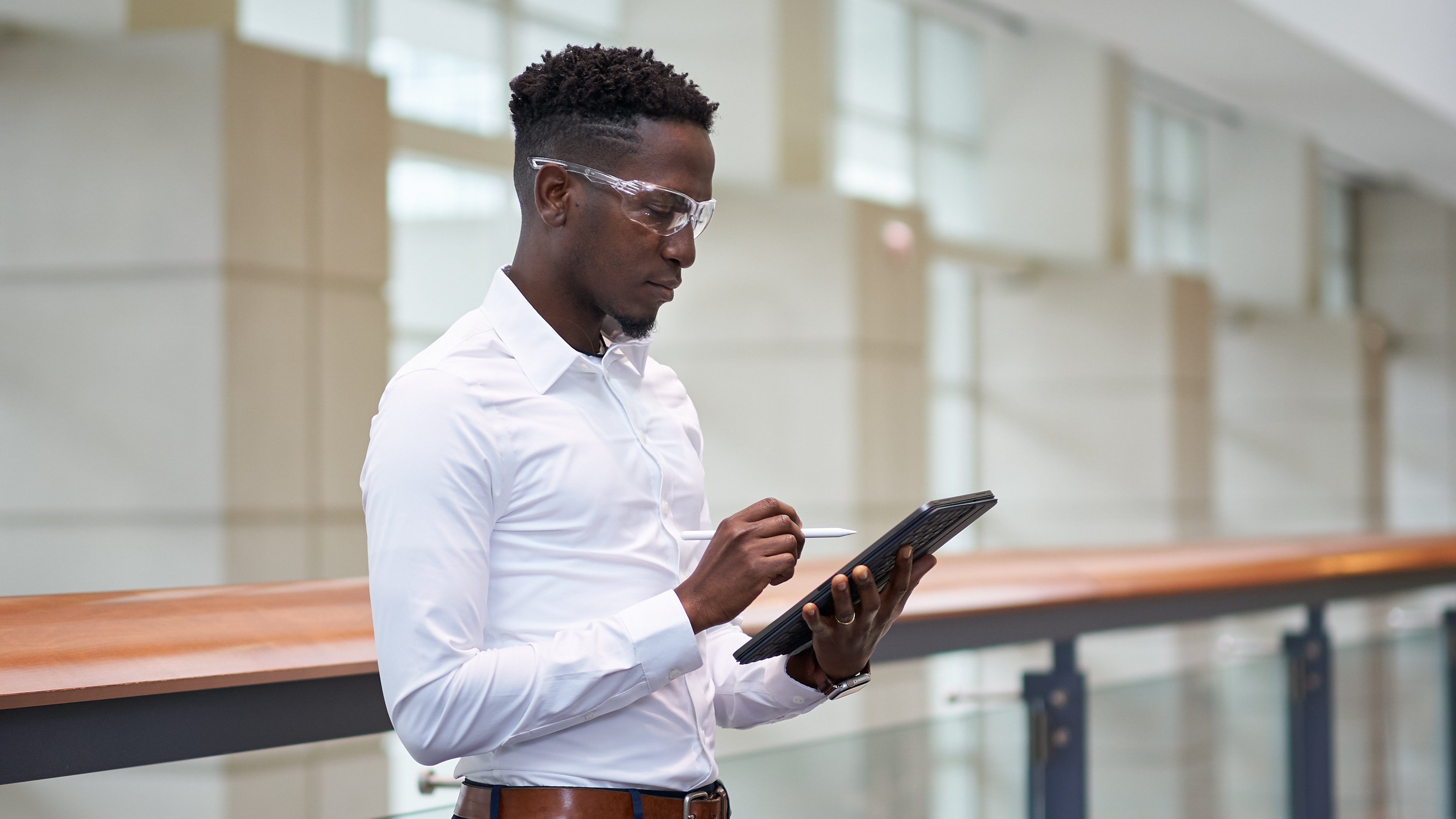 Engineer standing in a hallway using tablet with safety glasses on
