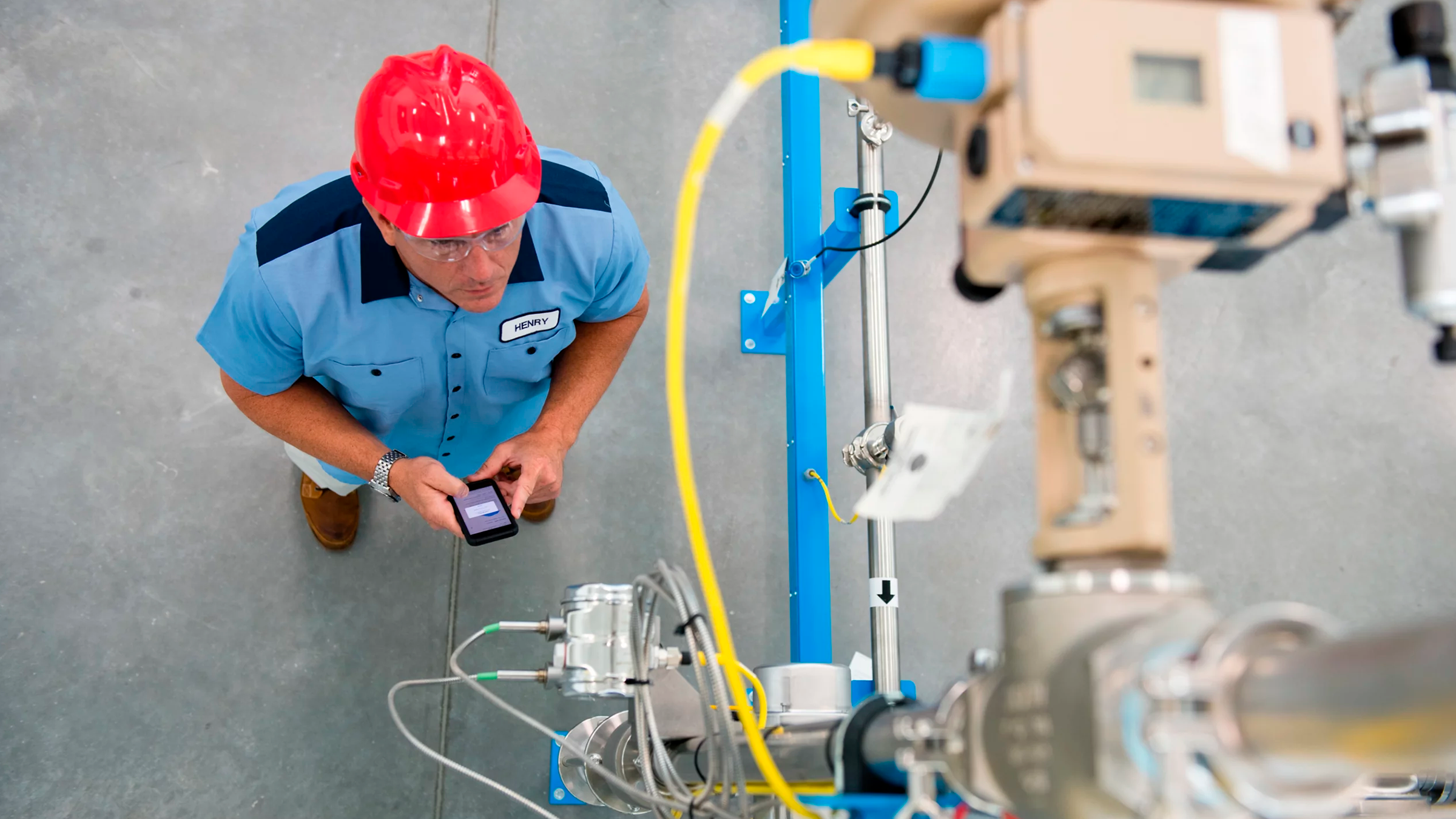 Ingeniero supervisando el funcionamiento de una máquina con su teléfono celular