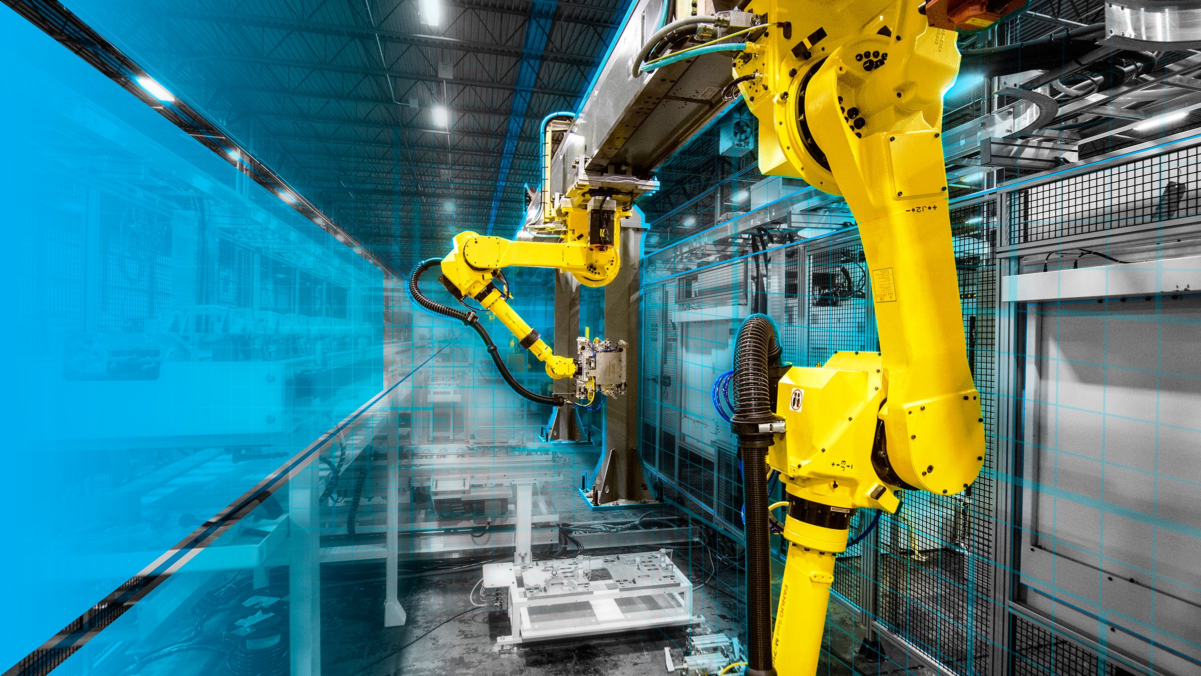 A machining system with Fanuc robots mounted upside down on rails with a blue hue surrounding the system.