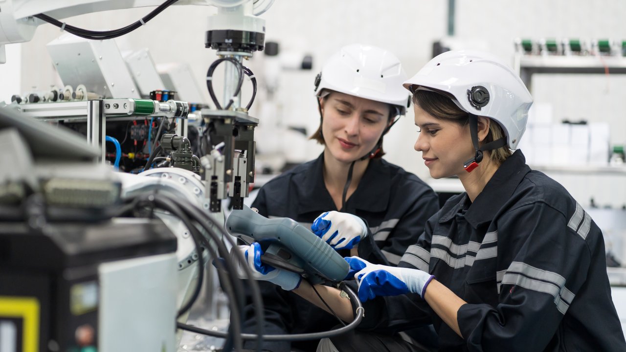 Two female engineers controlling autonomous mobile robot in the manufacturing automation and robotics academy room.