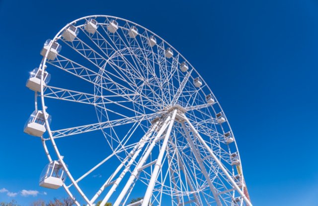 Ferris wheel under blue sky, capturing fun and adventure on a sunny day. Ferris wheel at the amusement park adjacent to the hotel