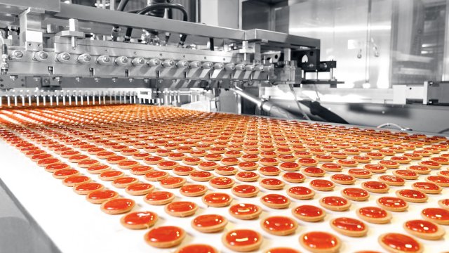 Cookies with orange filling on a conveyor belt at a food production factory. 