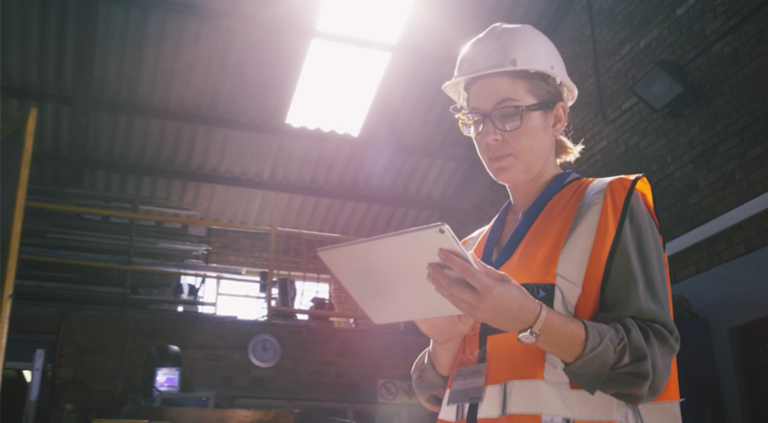 Female wearing safety gear looking at information on a tablet