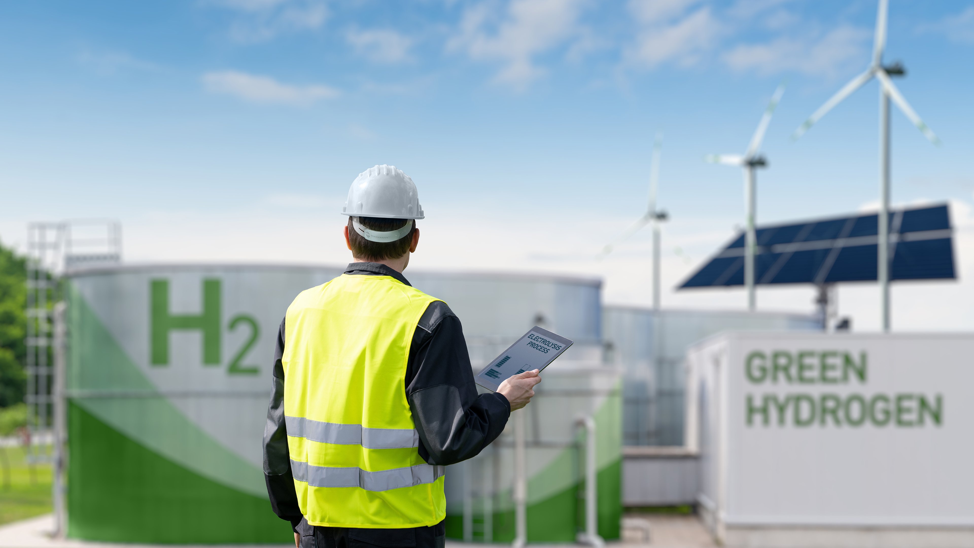 Engineer with tablet computer on a background of Green Hydrogen factory