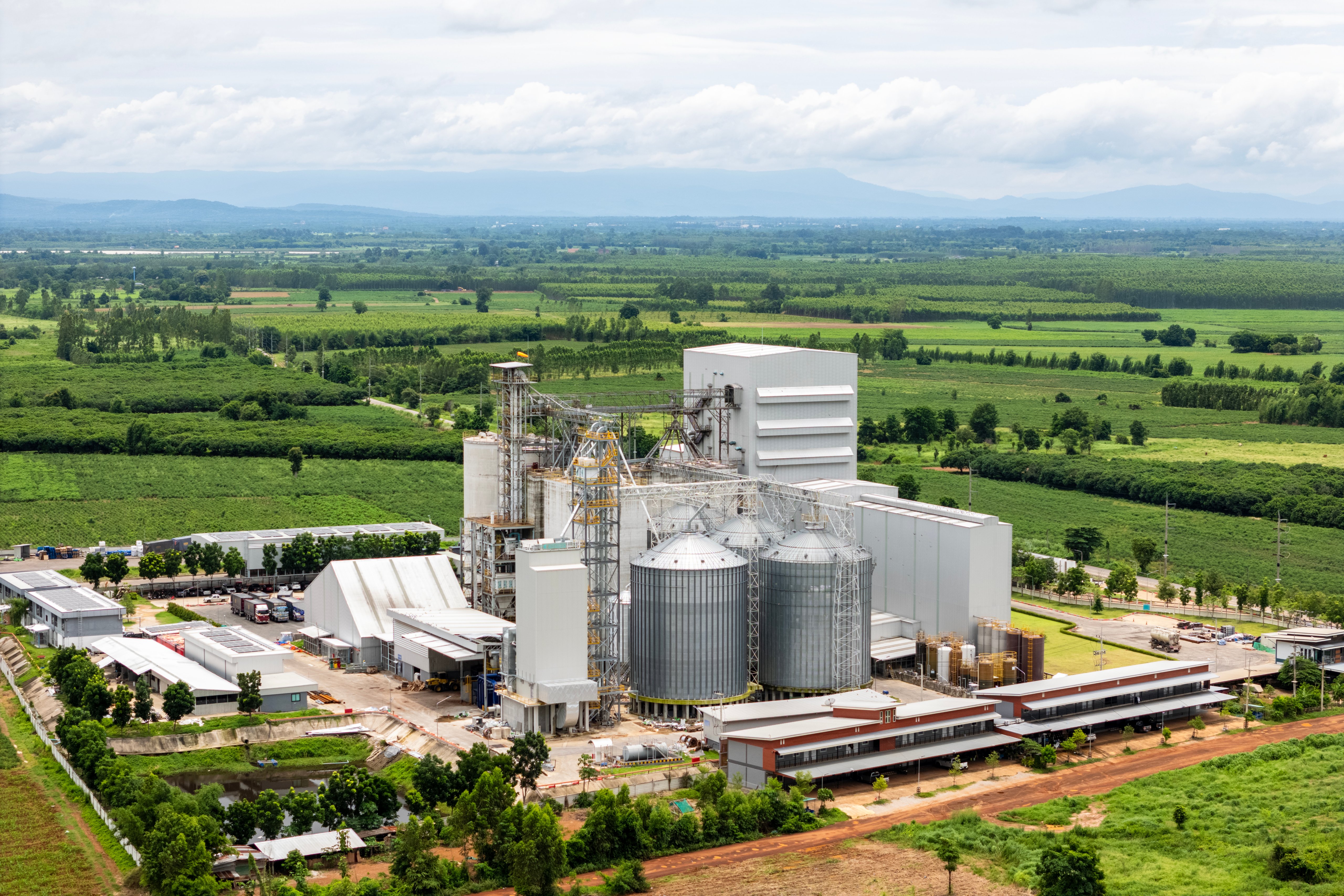 A large grain processing factory surrounded by green fields.