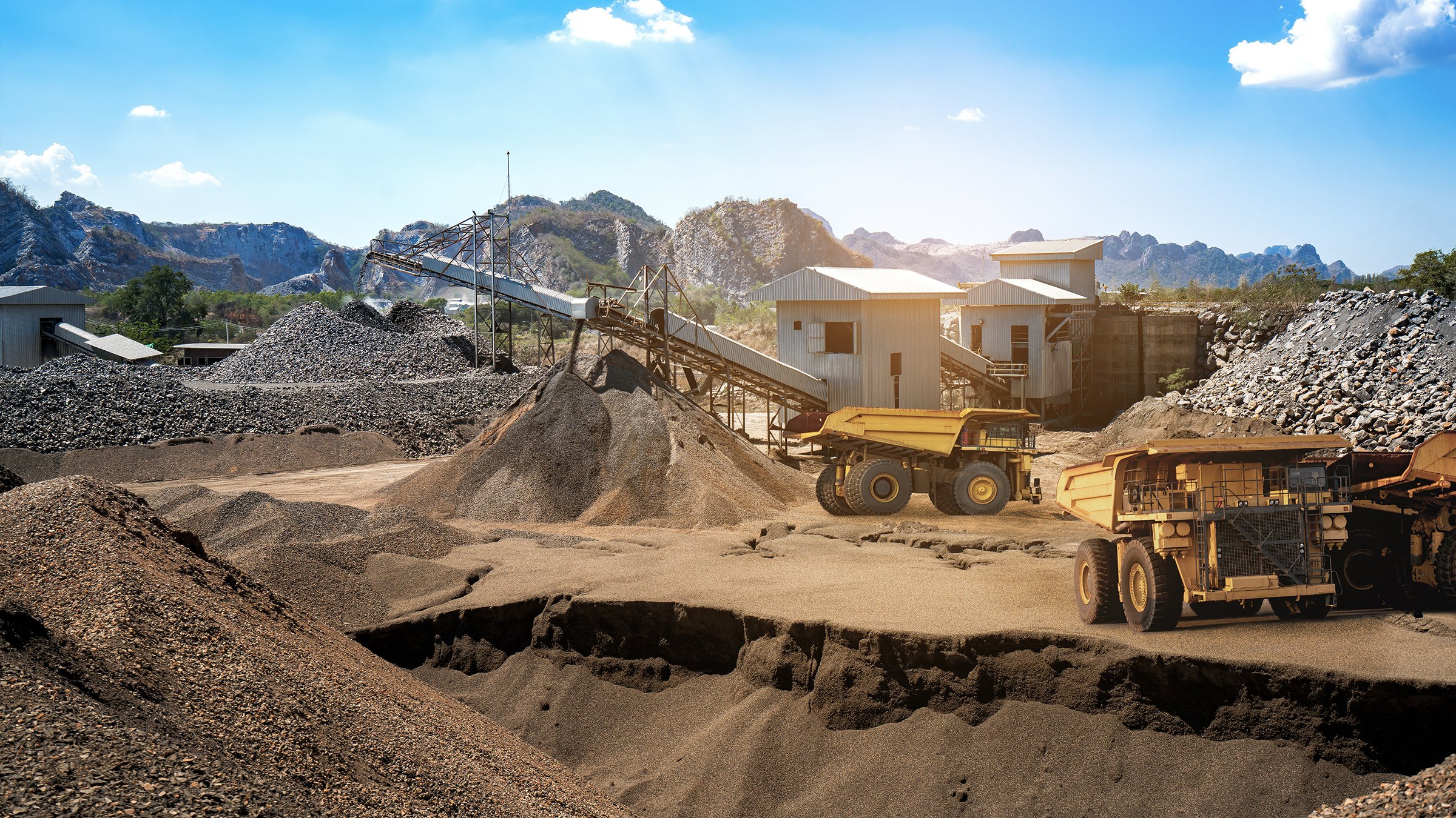 Yellow dump truck loading minerals copper, silver, gold, and other  at mining quarry.