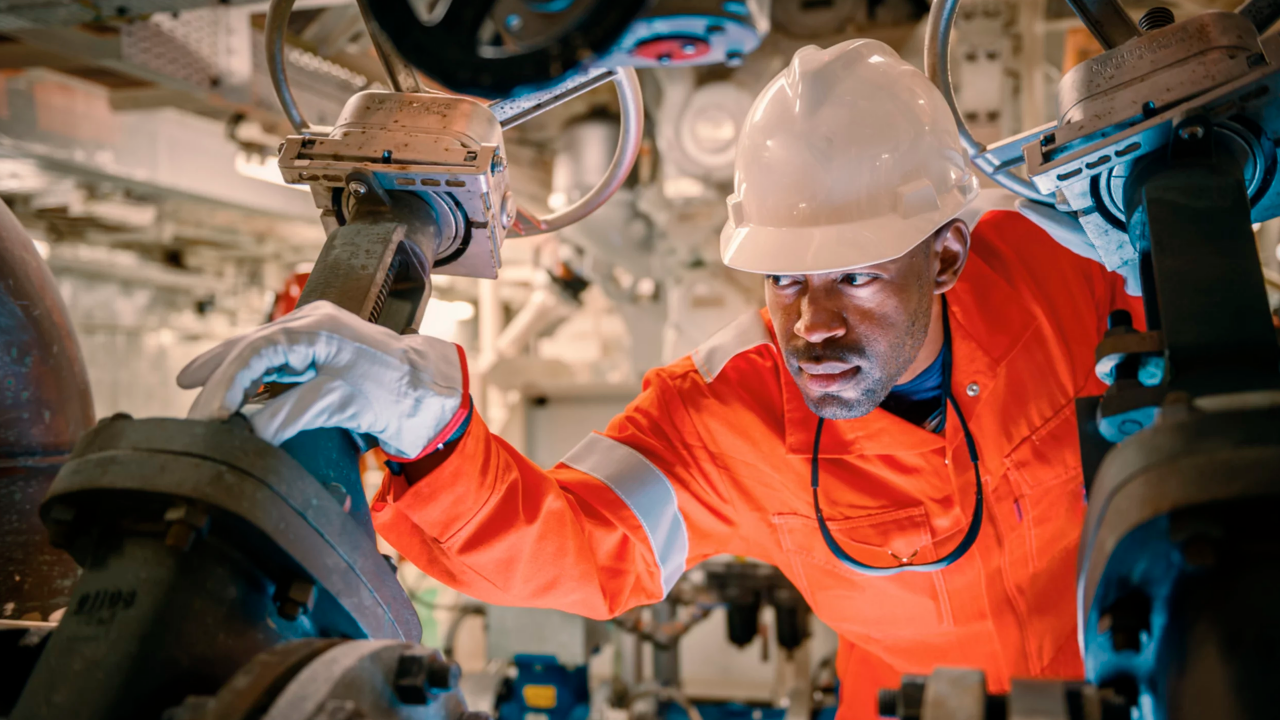 Man in safety suit conducting maintenance on a pipe