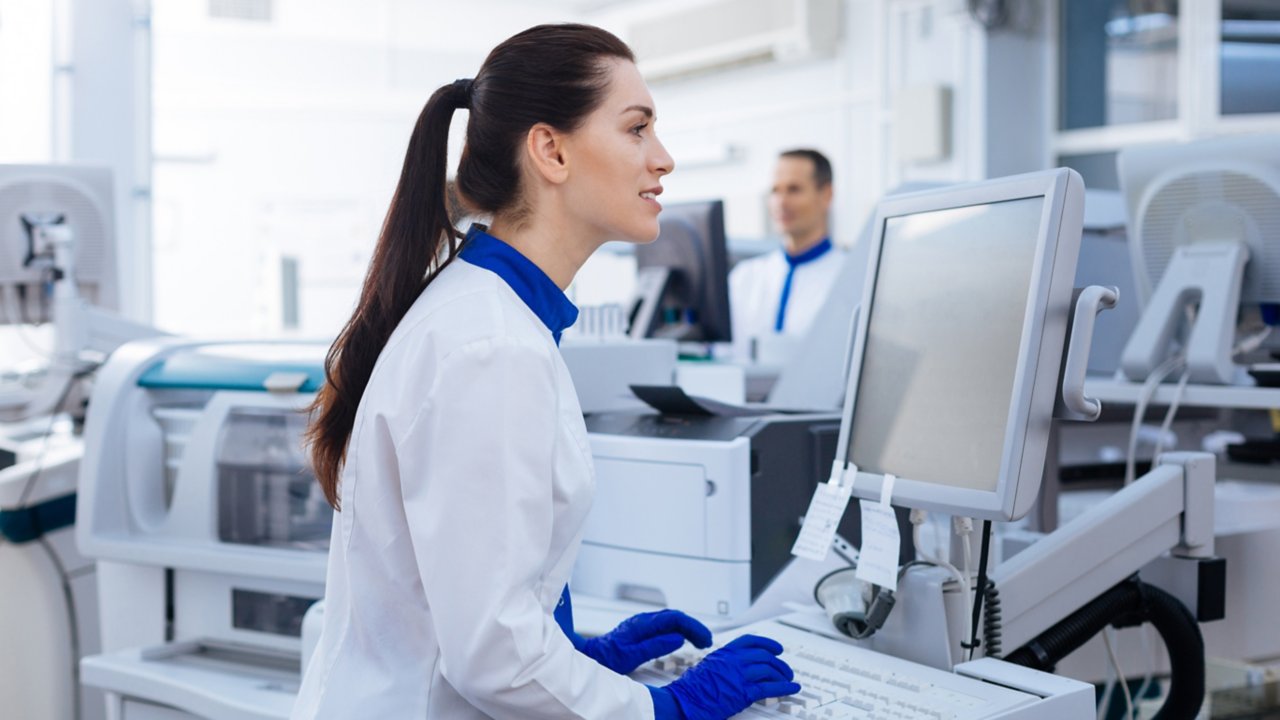 Woman with long ponytail in lab with computer screen