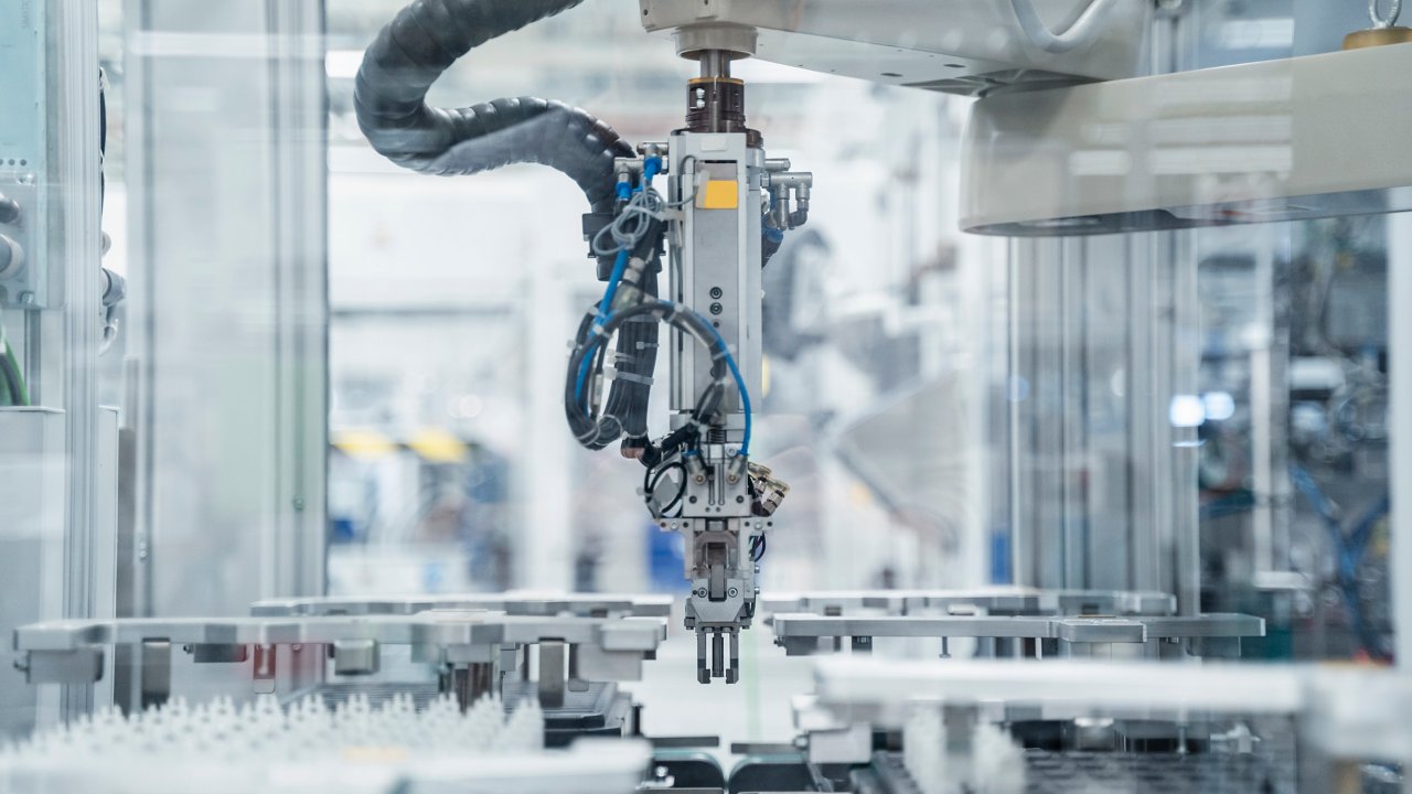 A grey custom SCARA robot inside of an assembly machine with a modern life sciences facility blurred out in the background.