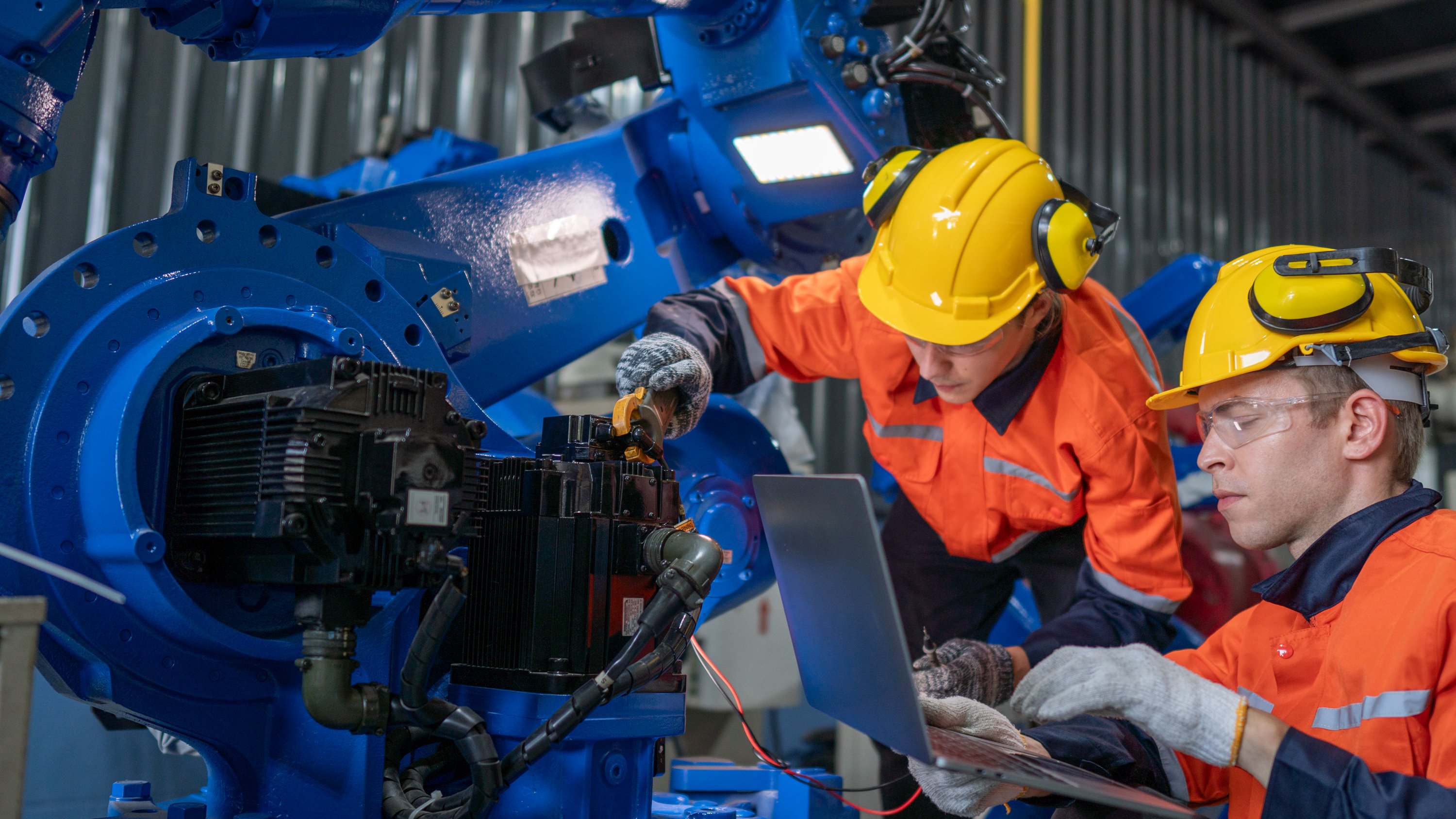 worker checking and repairing automatic robot hand machine. Worker wearing safety glasses and helmet