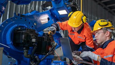 worker checking and repairing automatic robot hand machine. Worker wearing safety glasses and helmet