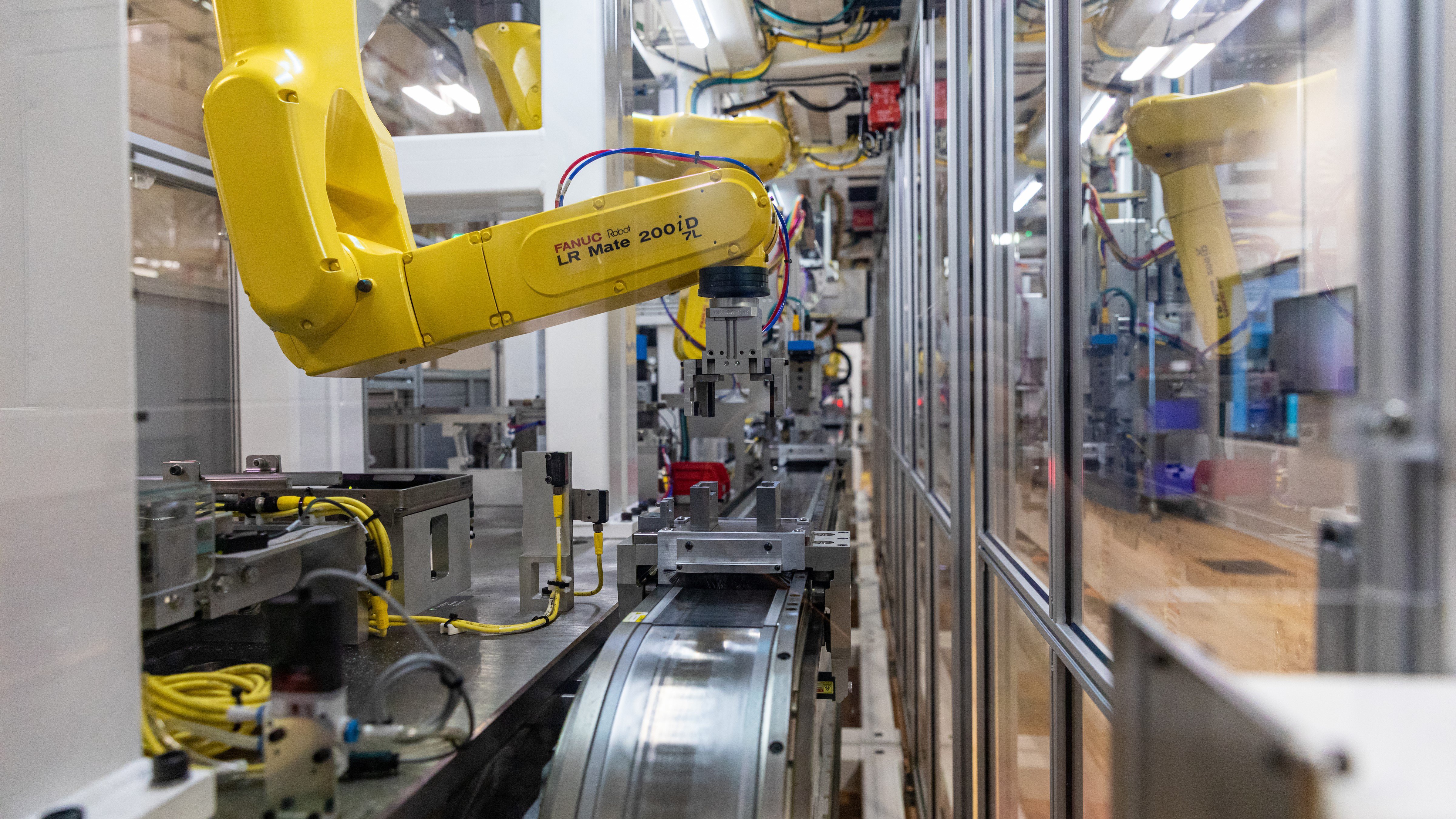 An iTRAK intelligent track system carrying products from station to station where FANUC robots are doing assembly tasks.