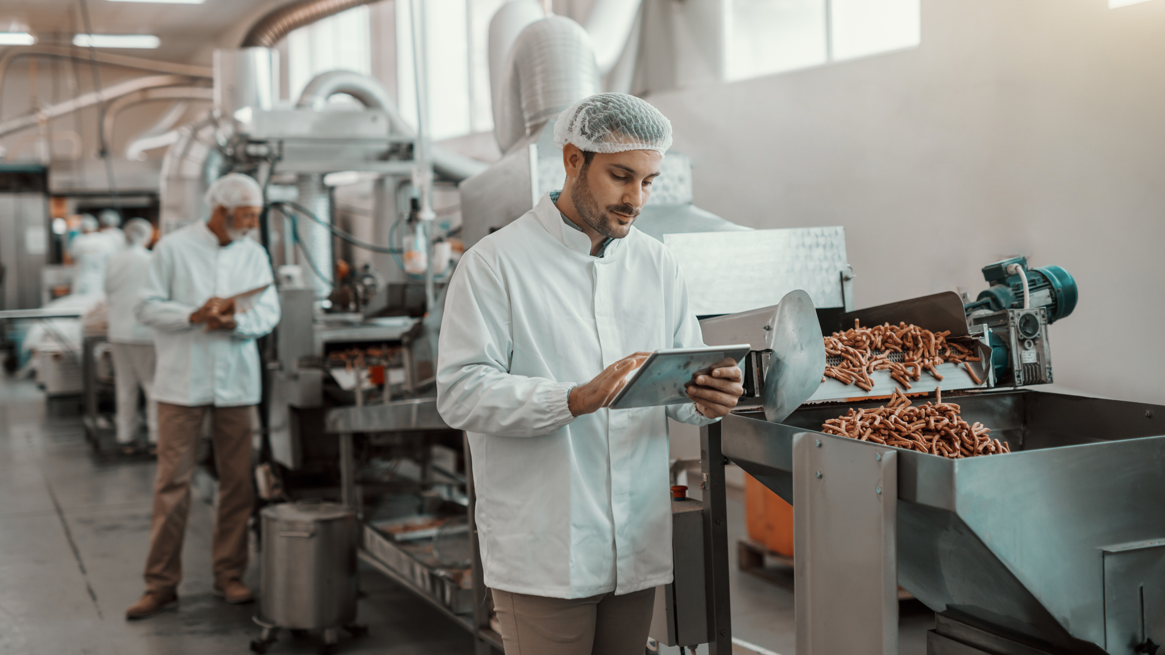 Male engineer analyzing Plex Smart Manufacturing software tool, food processing equipment in background 