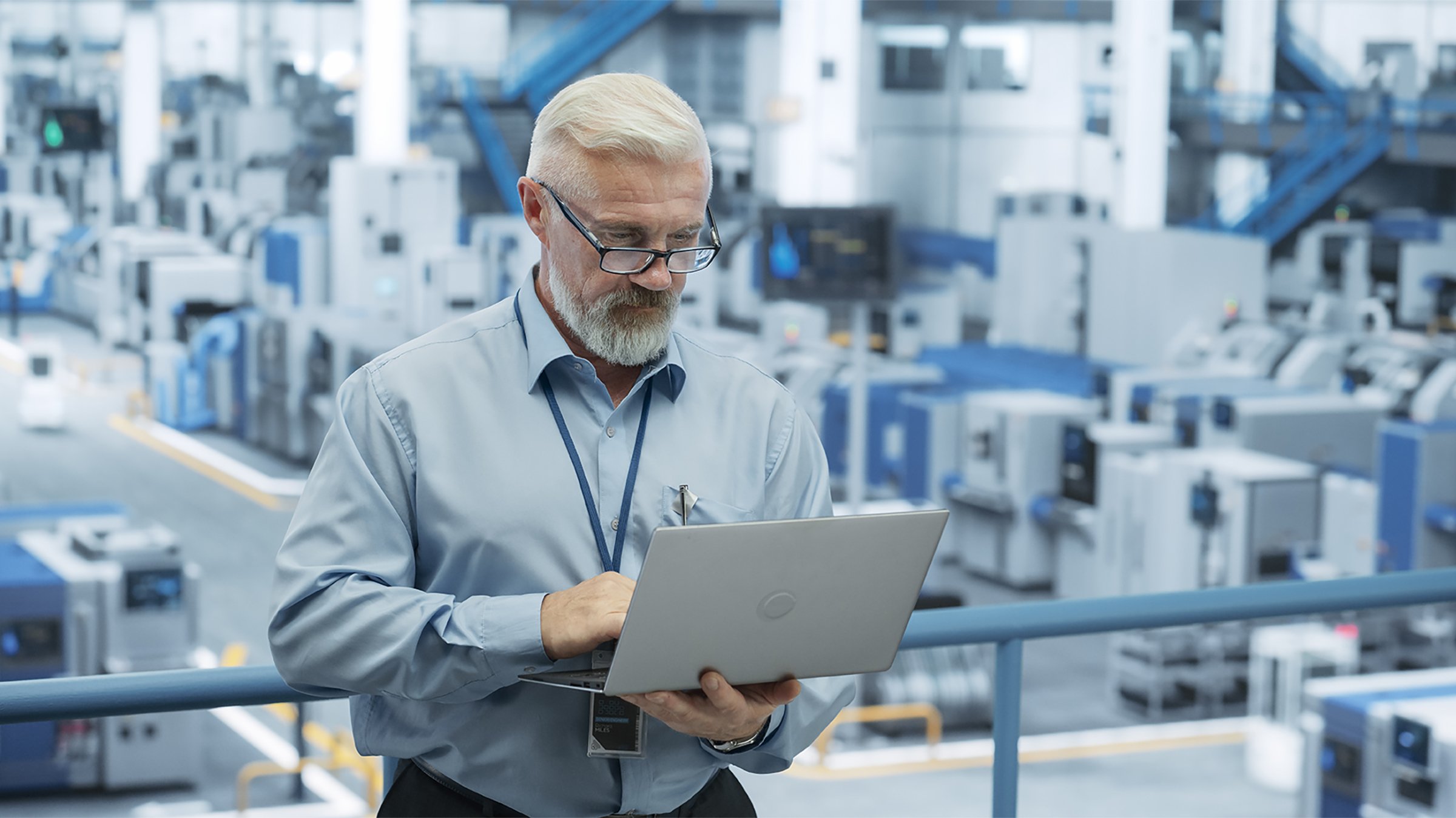 Middle Aged Engineer Monitoring and Analyzing Conditions at an Automated Modern Electronics Factory with Mobility Robots Working with the Help of Artificial Intelligence Software