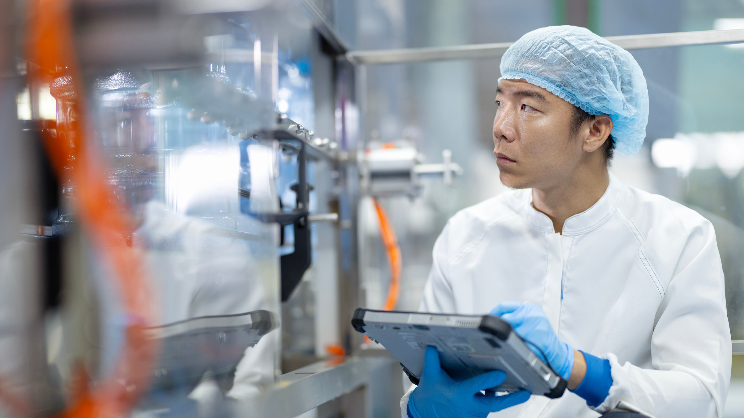 A male engineer uses a tablet  to inspect the process and machinery in food manufacturing setting