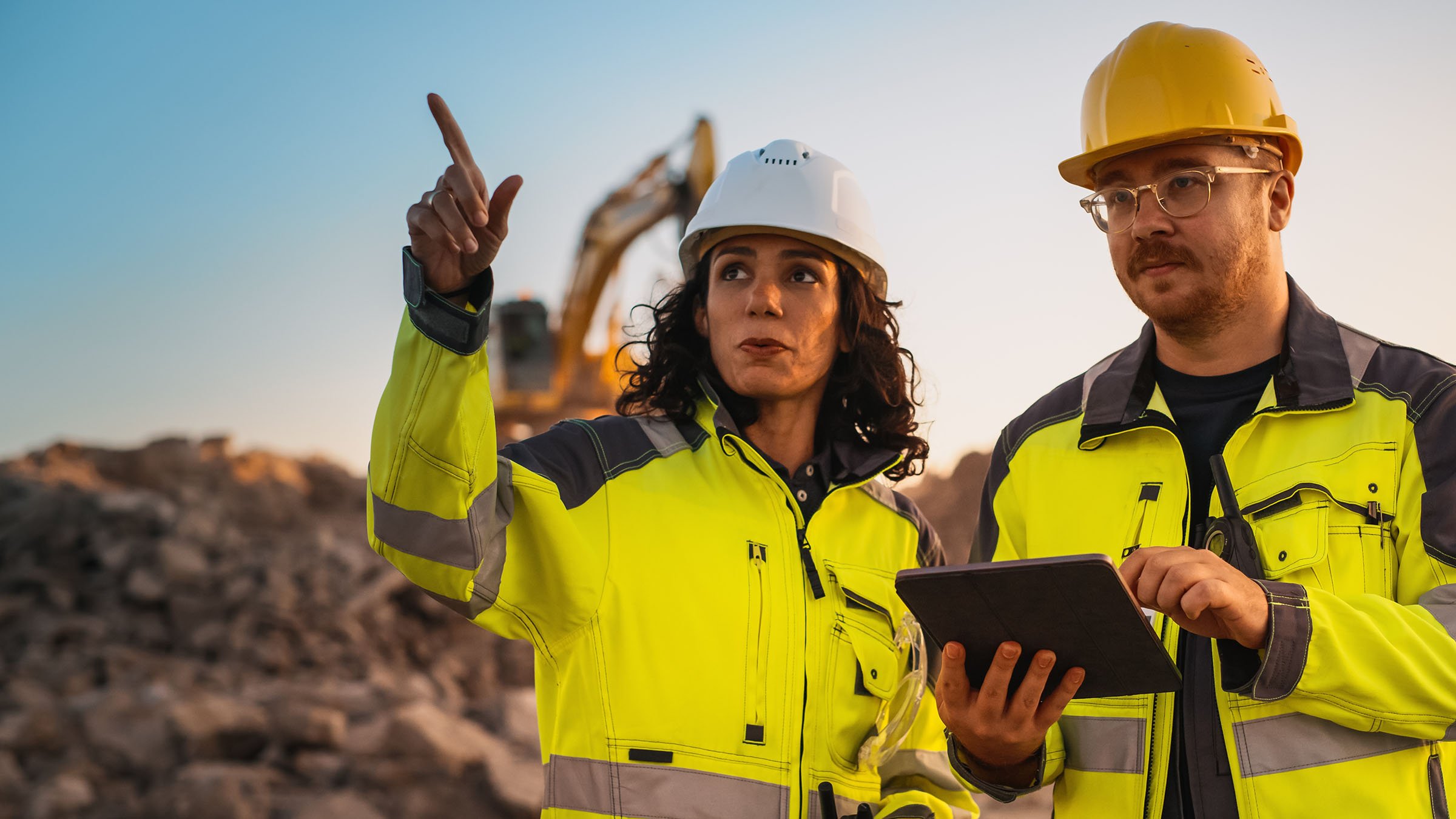 Male Engineer Talking To Female Inspector  Using Tablet Computer On Construction Site . Female is pointing.