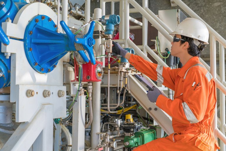 Man in orange jumpsuit turning valve of machine