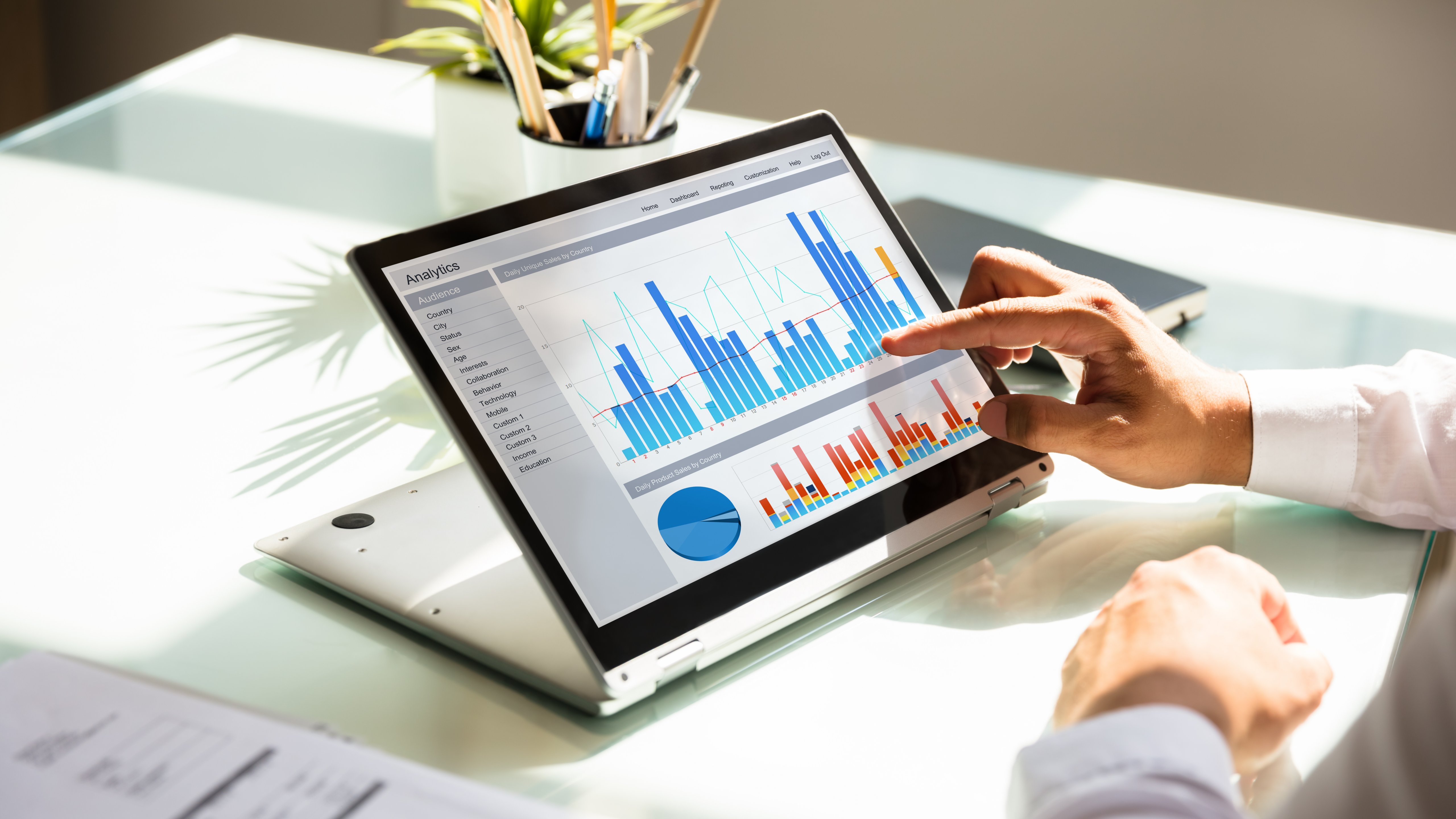 Man pointing on a screen with graphs on laptop