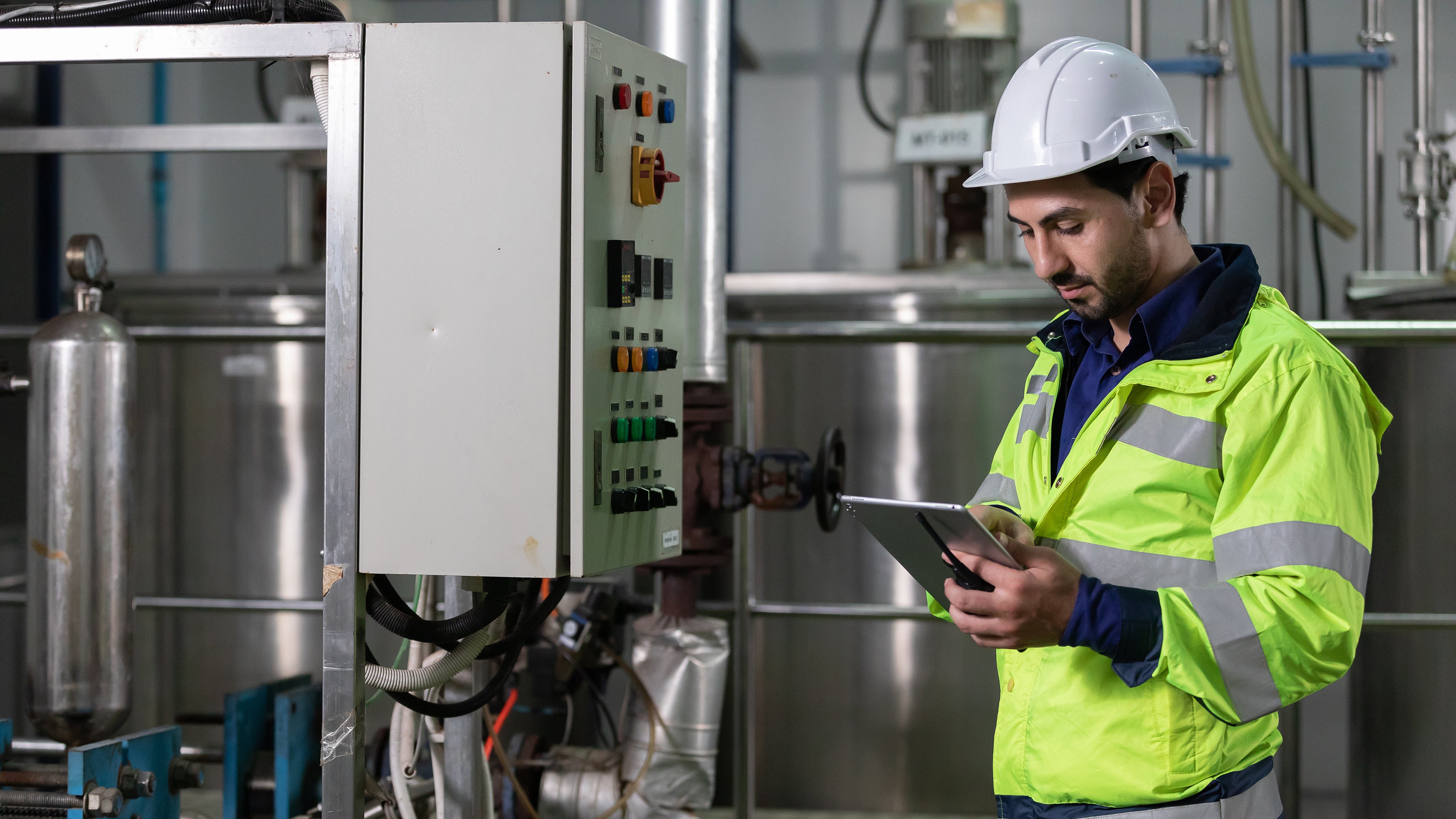 engineer or factory worker using tablet computer for finding how to use machine control panel in factory