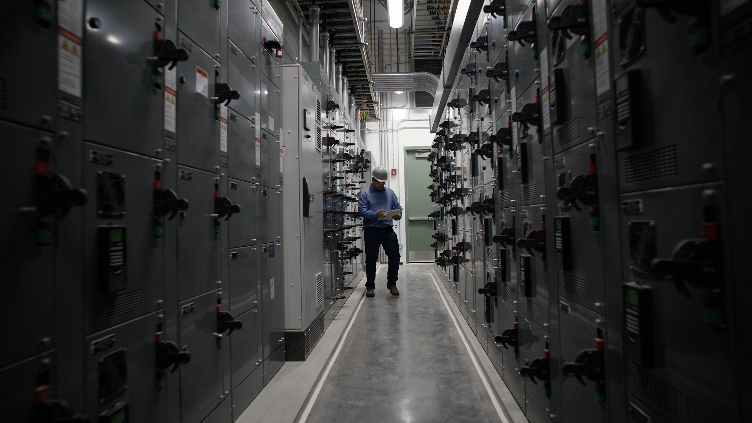 man with tablet working amongst motor control centers in a greenfield facility