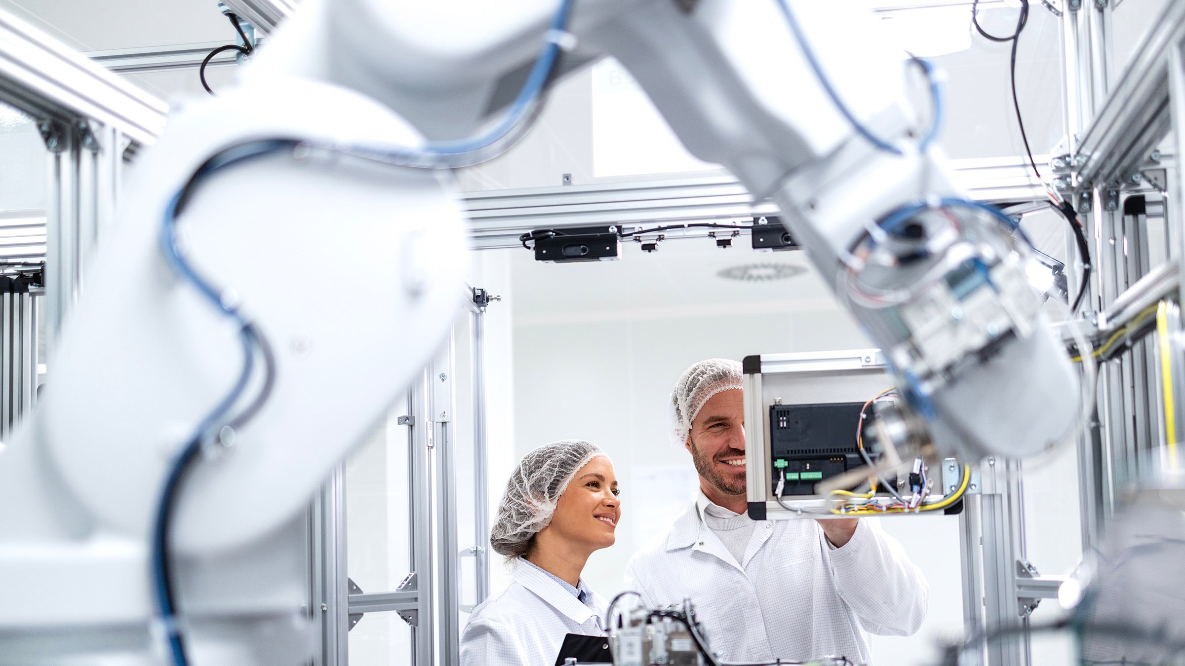 Technology specialists monitoring artificial intelligence of robotic machines inside the factory.